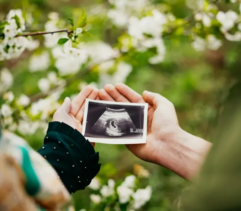 Woman holding ultrasound photo among blossoms